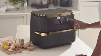 Air Fryer : 5 critères essentiels avant d’acheter air fryer double cuve sur un plan de travail avec une main qui le touche