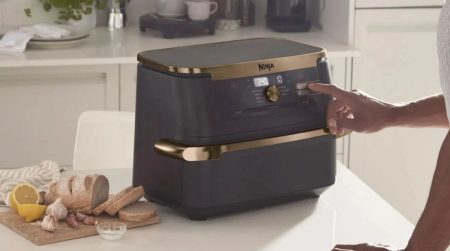 air fryer double cuve sur un plan de travail avec une main qui le touche